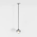 Clérachic silver-finish pendant light hangs on a black cord, glass sphere shade lit against a white backdrop.