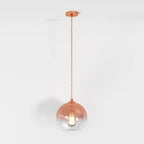 Clérachic rose gold glass sphere pendant shown at full drop length, filament bulb lit on a white studio ground.