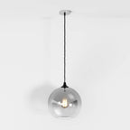 Clérachic silver-finish pendant light with gradient glass sphere shade, filament bulb glowing on white backdrop.