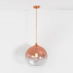 Clérachic rose gold glass sphere pendant on a matching cord, warm filament bulb glowing on white backdrop.