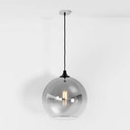 Clérachic silver-finish glass sphere pendant on a black cord, warm filament bulb glowing on white backdrop.