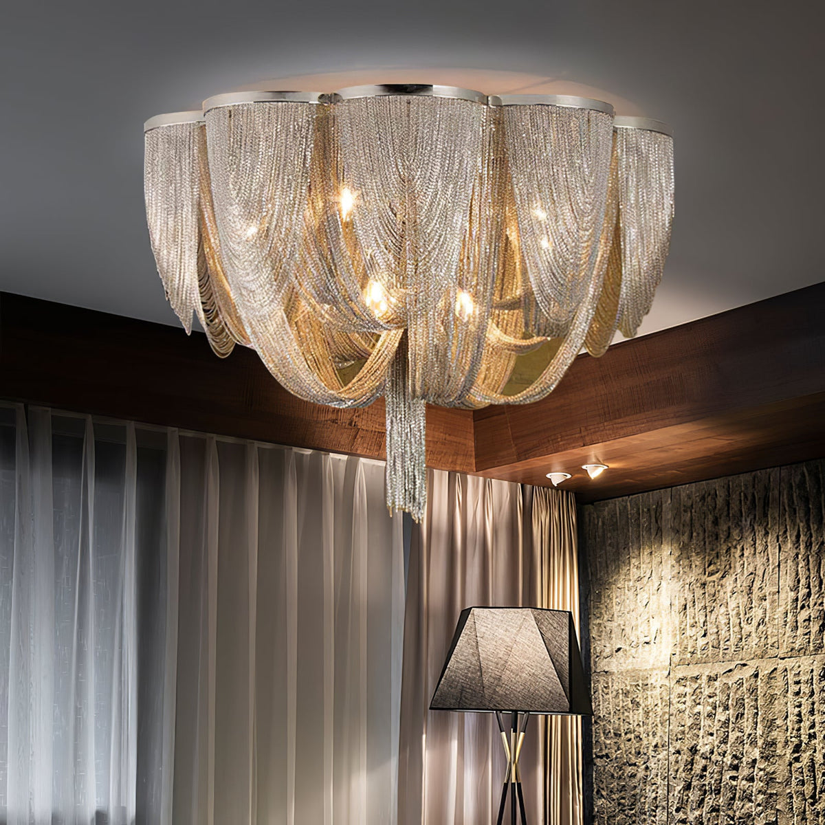 Clérachic silver chain ceiling light with draped swags and a centre tassel, above curtains and a stone feature wall.