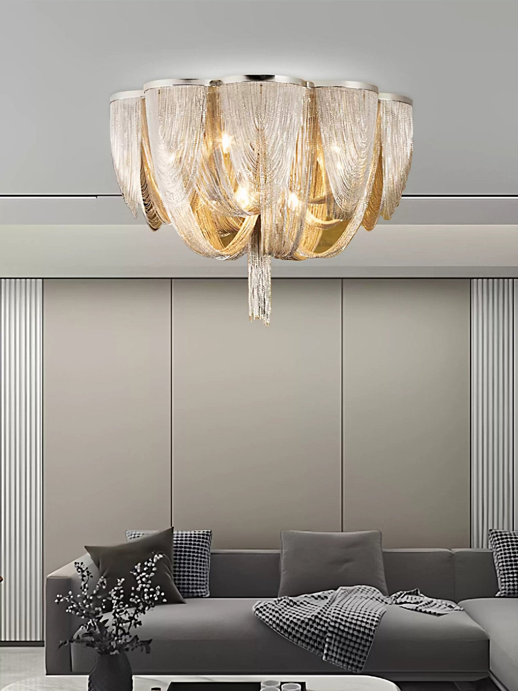 Clérachic silver chain ceiling light above a grey sofa with a throw, against a pale wall with vertical panels.