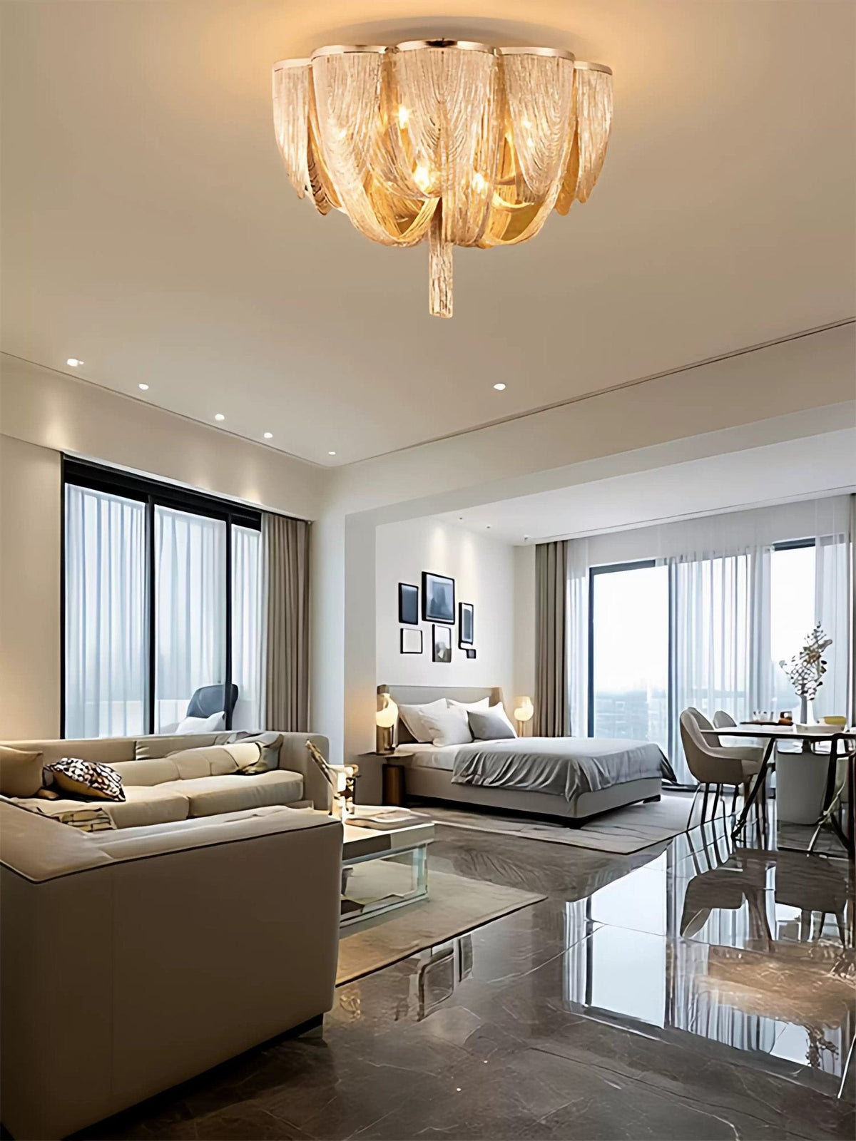 Small Clérachic chain ceiling light glowing gold in the ceiling of an open-plan room with a bed and sofa seen beyond.
