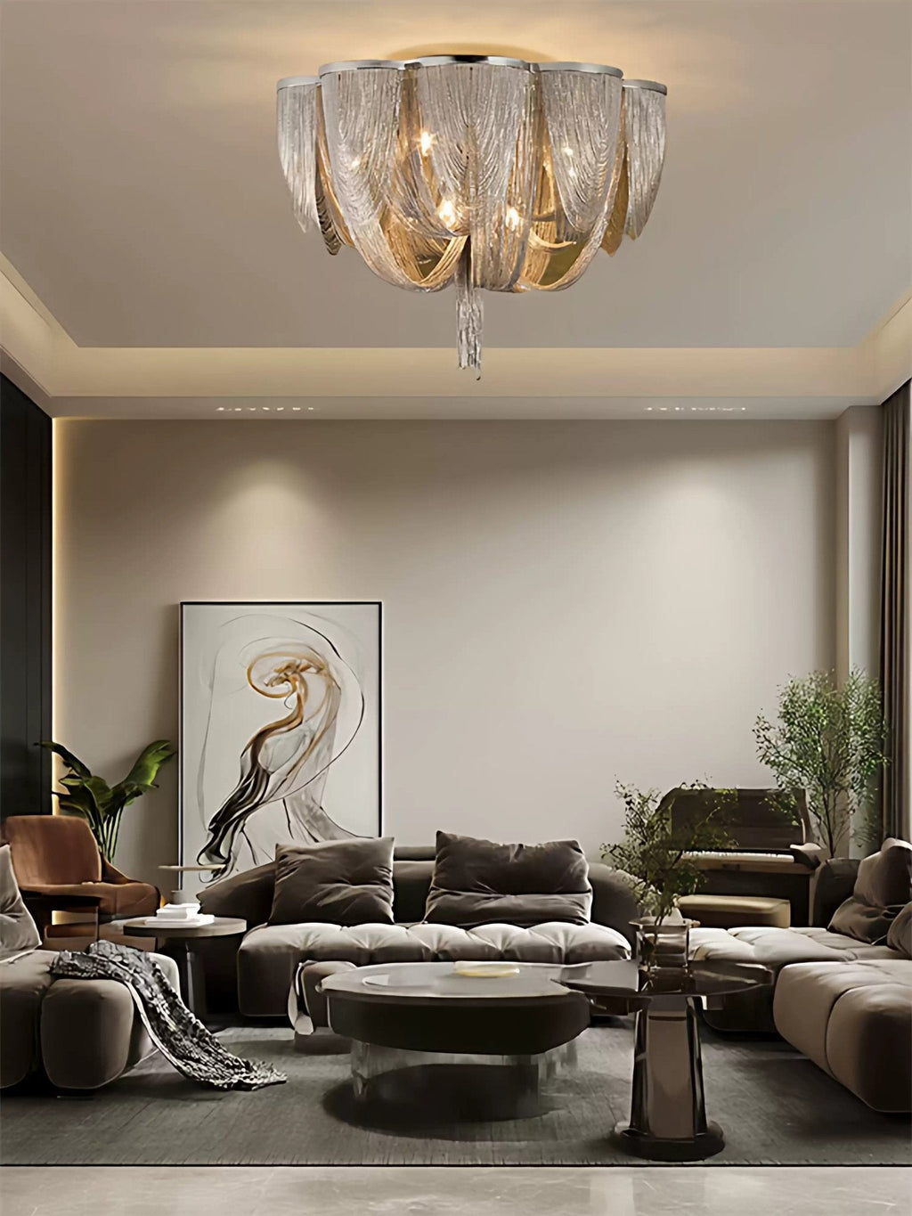 Clérachic chain ceiling light above a living room with a modular sofa, a large abstract print and a glass coffee table.