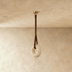 Clérachic unlit alabaster ring pendant light with veined white stone, brown leather strap and gold canopy on limewash.
