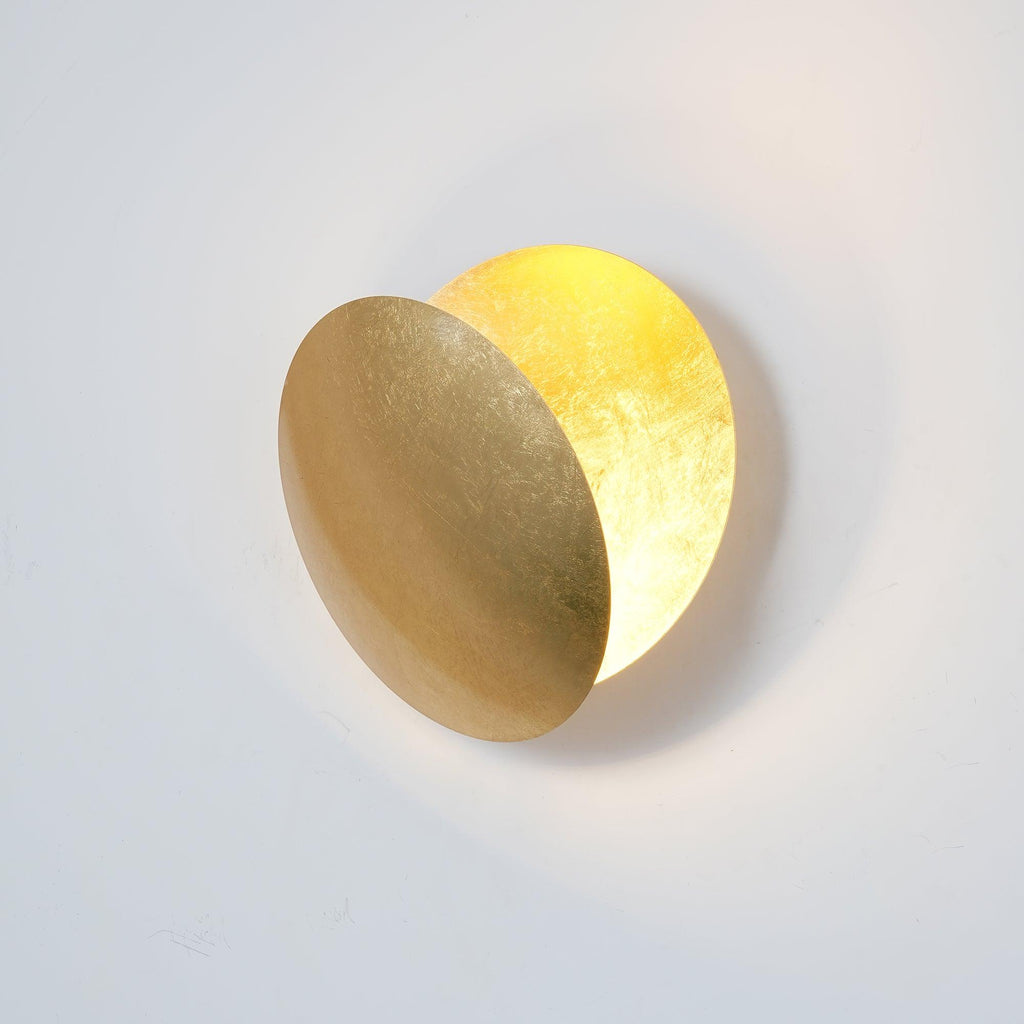 Side-on view of this Clérachic wall light, a gold front disc tilted away from the wall to show the glowing gold disc behind.