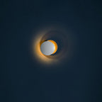 Small Clérachic wall light on a dark navy wall, a pale disc beside a gold one, with a faint amber light along the rim.