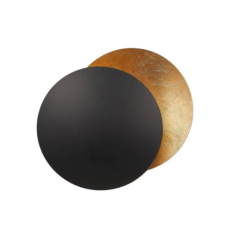 Large front view of the black and gold Clérachic wall light, a matt black disc half covering a mottled gold disc.