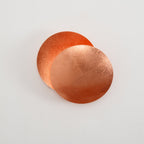 Copper Clérachic wall light on a pale wall, two overlapping discs with the rear disc cupped and glowing orange inside.