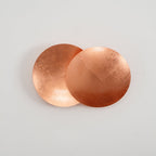 Straight-on view of this copper Clérachic wall light on a white wall, the rear disc curved like a shallow dish behind the flat front disc.