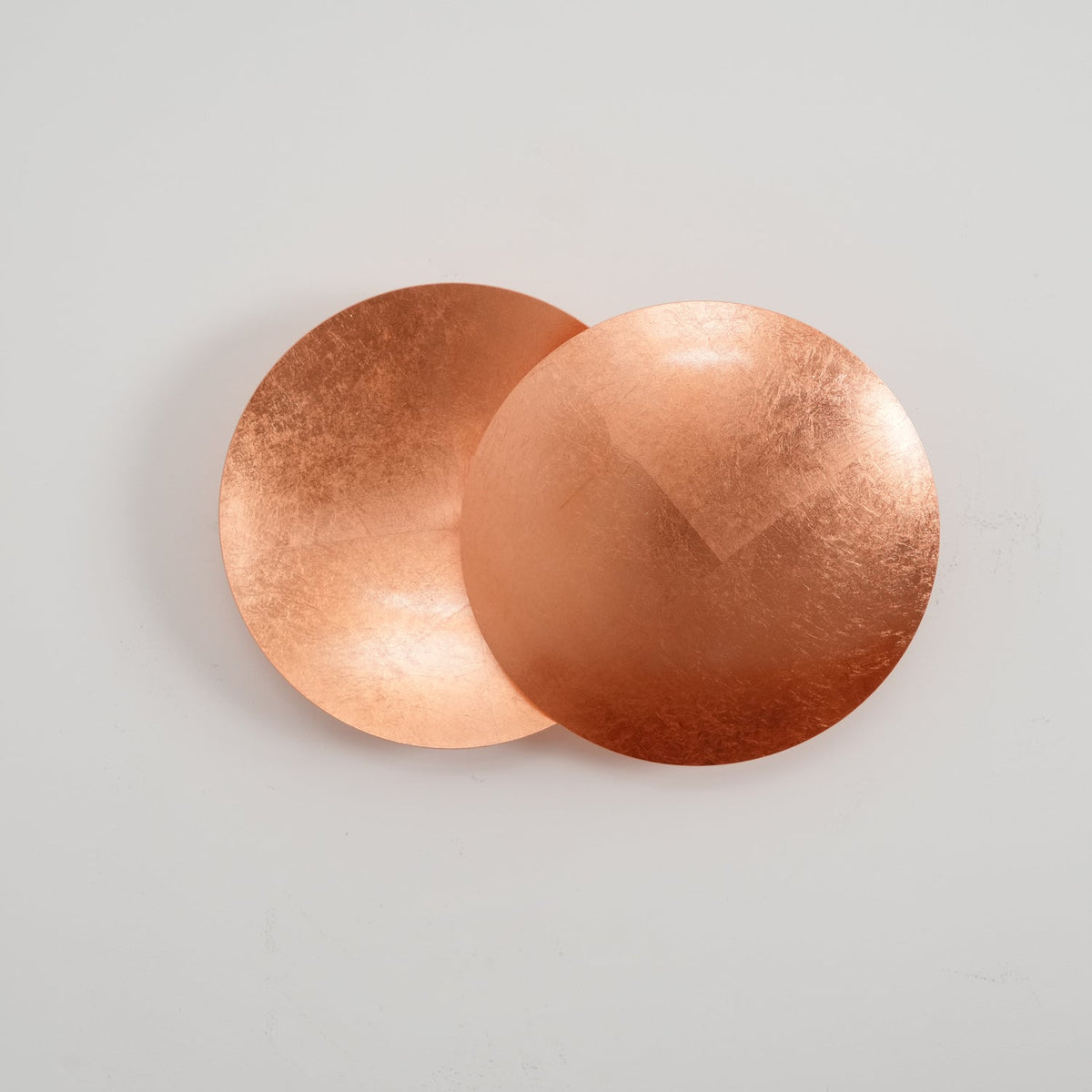 Copper Clérachic wall light shown larger on a white wall, the front disc a little lighter than the cupped disc behind.