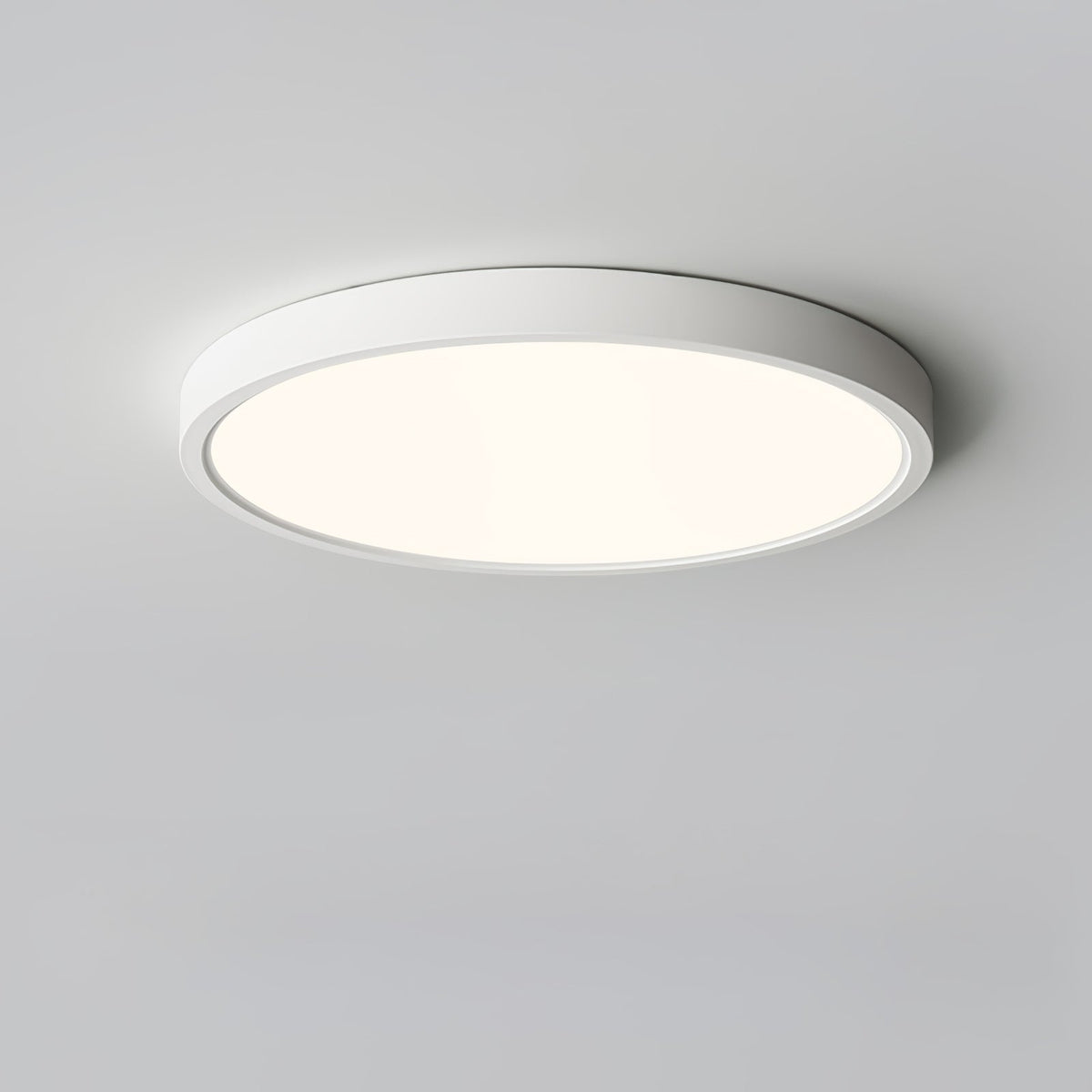 A white Clérachic round ceiling light with a gentle warm-toned glow, shown from slightly below on a pale grey ceiling.