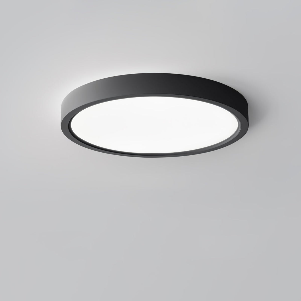 A black Clérachic round ceiling light with a bright white diffuser, angled so that its slim black edge shows against grey.