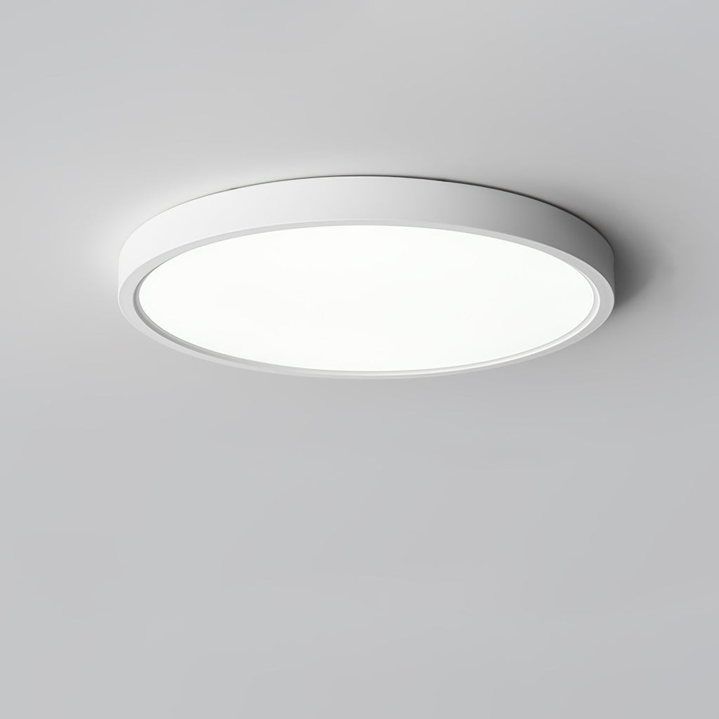 Seen from below at a slight angle, a white Clérachic round ceiling light with a bright diffuser on a grey ceiling.