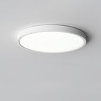 Seen from below at a slight angle, a white Clérachic round ceiling light with a bright diffuser on a grey ceiling.