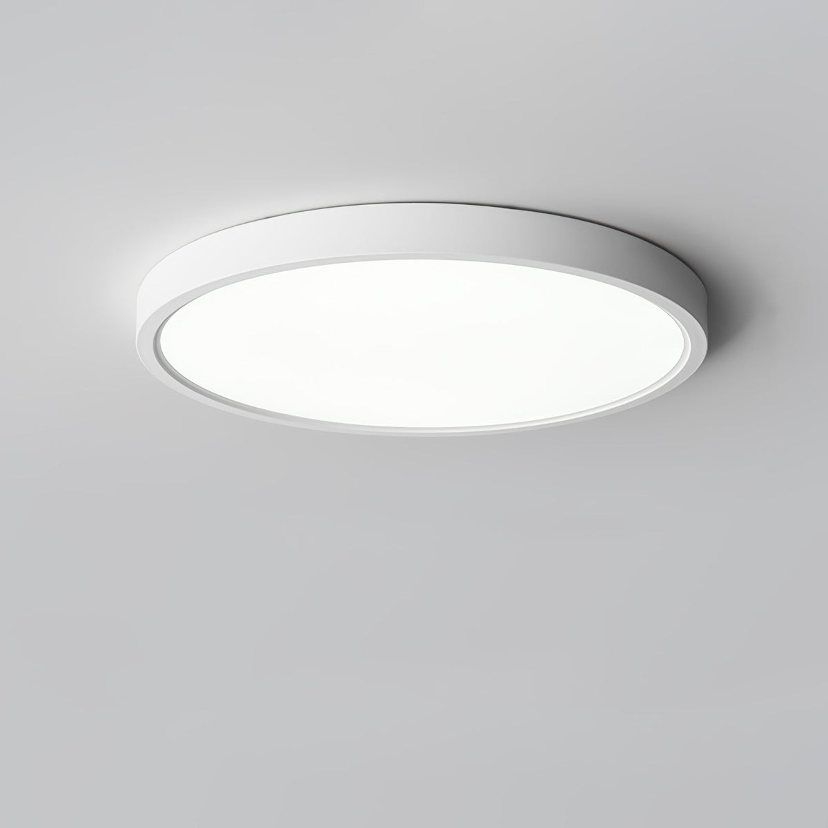 Seen from below at a slight angle, a white Clérachic round ceiling light with a bright diffuser on a grey ceiling.