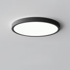 A black Clérachic round ceiling light with a flat white diffuser and a thin black rim, against a plain grey ceiling.