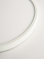 Close view of the thin curved white edge of this Clérachic ceiling light, with the soft glow of the diffuser along its inner lip.