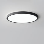 A black Clérachic round ceiling light with a bright white diffuser, seen from a low angle on a plain grey ceiling.