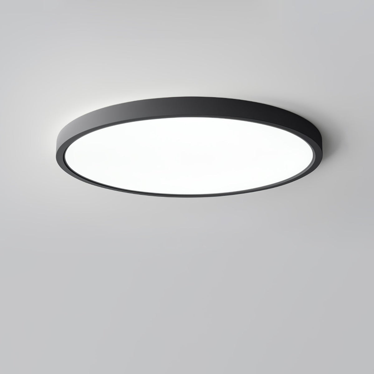 A black Clérachic round ceiling light with a bright white diffuser, seen from a low angle on a plain grey ceiling.
