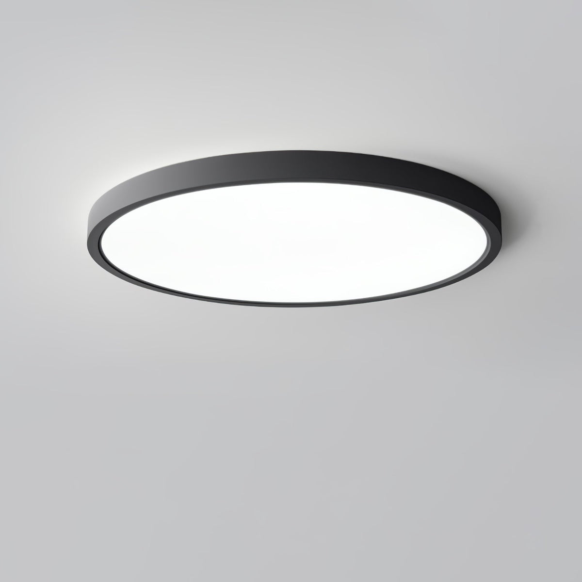 A black Clérachic round ceiling light with a large flat white diffuser, photographed from slightly below against a grey backdrop.