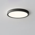 A black Clérachic round ceiling light with a warm glow, viewed from a low angle against a soft grey-lilac ceiling.