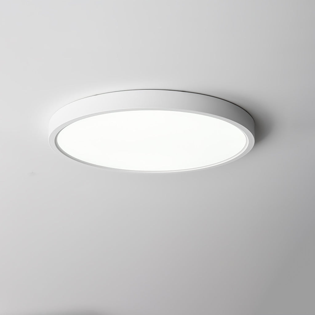 Cool white light from a white Clérachic round ceiling light with a thin white edge, on a pale grey ceiling.