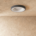 Clérachic grey round ceiling light switched off, showing its white diffuser and slim grey rim on limewash plaster.