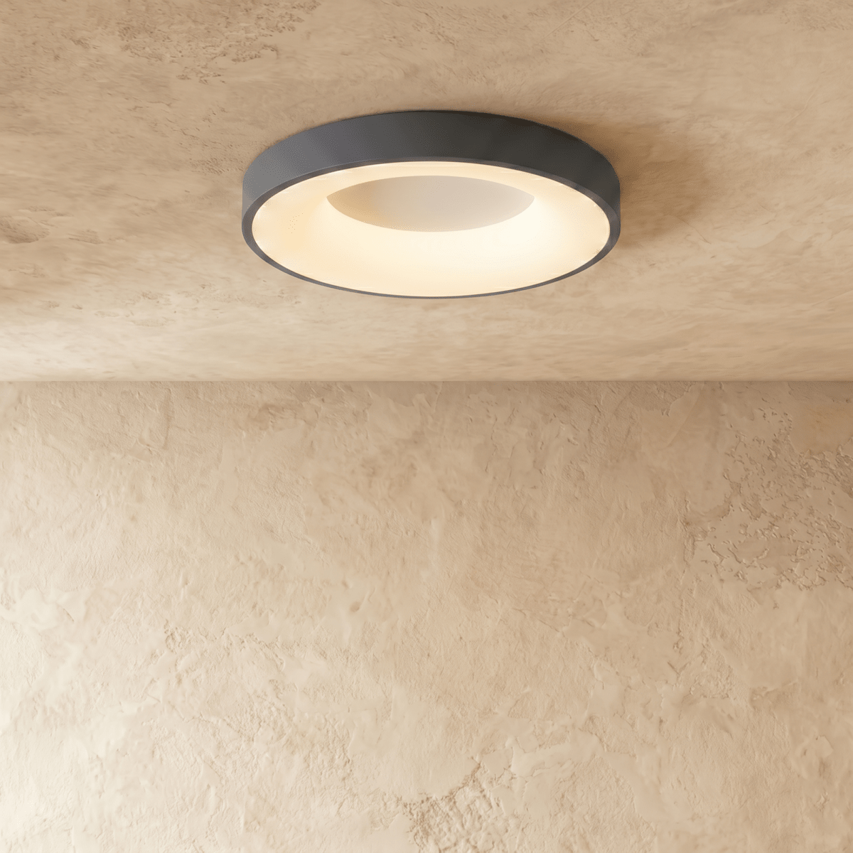 Clérachic grey round ceiling light, a slightly larger size, lit warm white above a softly textured plaster wall.