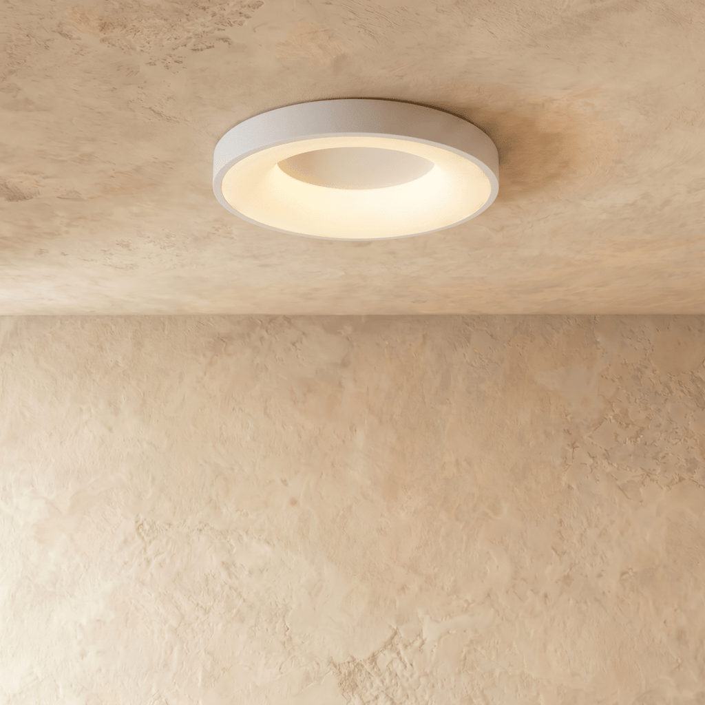 Clérachic white round ceiling light with a glowing inner ring, mounted flush on a textured limewash ceiling.
