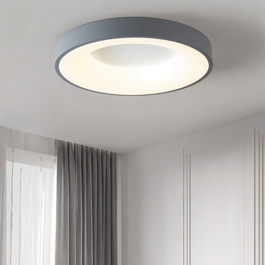 Clérachic grey round ceiling light in a calm bedroom corner, with grey curtains and a panelled wall beside it.