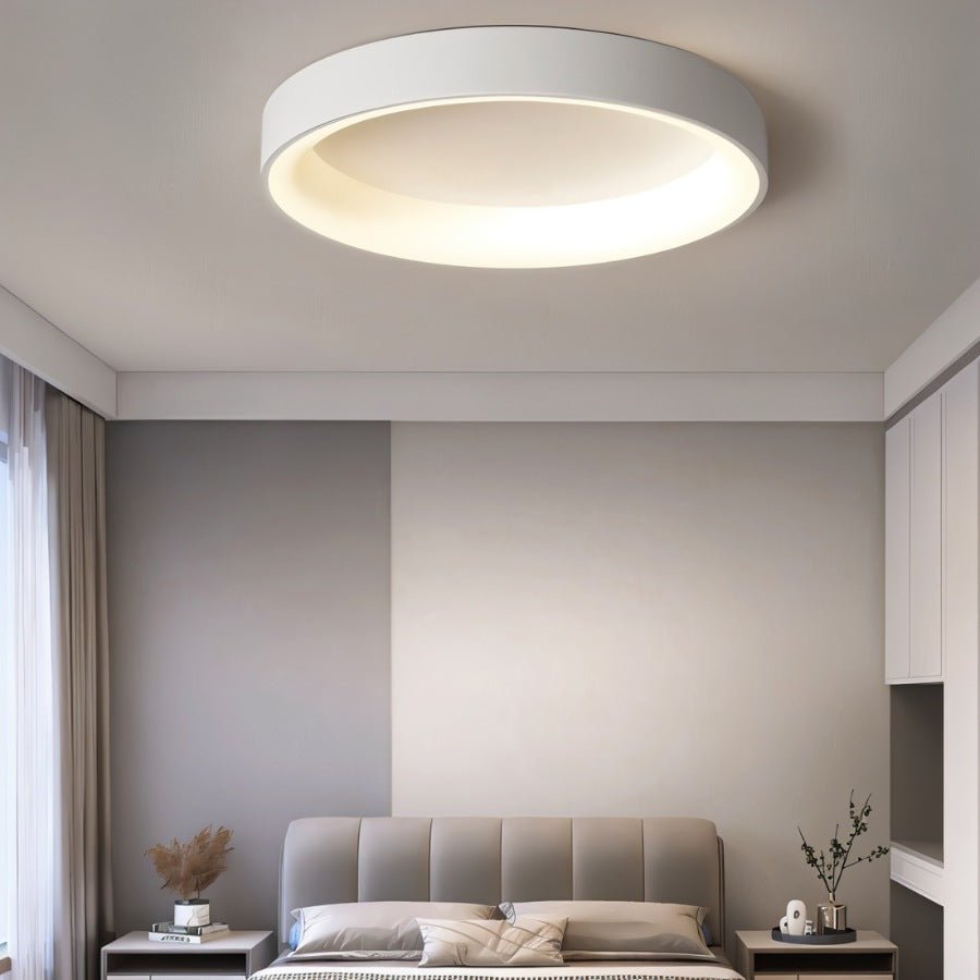 Clérachic white round ceiling light above a upholstered grey bed, with bedside tables and soft curtains below.