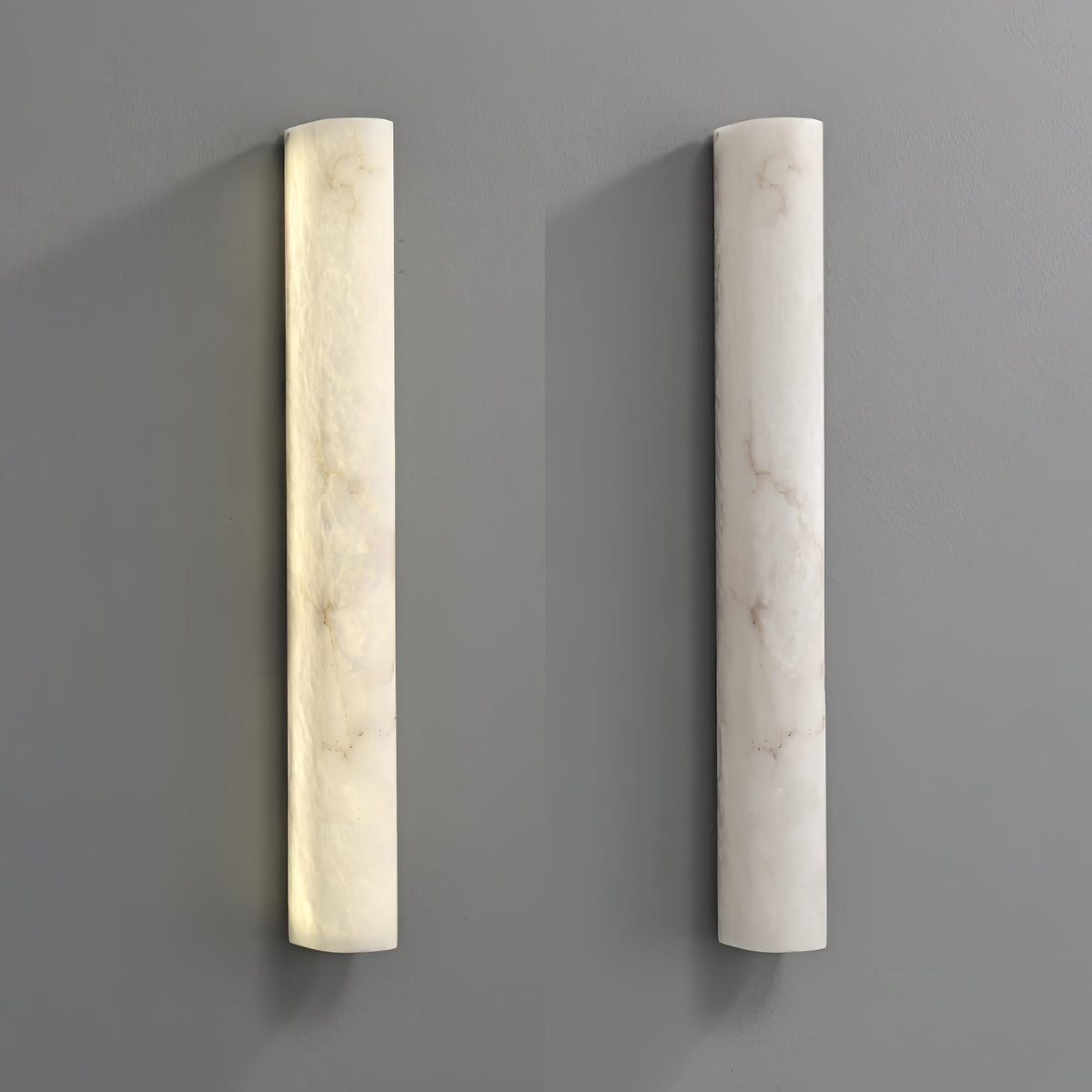 Two Clérachic alabaster sconces side by side on a grey wall, the left one lit and the right one switched off.