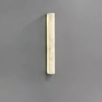 Shorter Clérachic sconce lit on a grey wall, the creamy alabaster face glowing evenly with soft marbling.