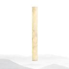 Slim alabaster column lit warm cream against a white backdrop with faint misty hills at its foot; this Clérachic wall light.