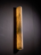 Side view of the glowing alabaster sconce against a dark wall, showing warm amber clouds in the stone; this Clérachic wall light.