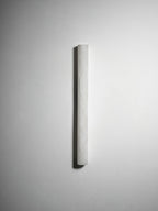 Unlit slim Clérachic alabaster sconce on a bright white wall, the half-round form casting a thin shadow on its left.