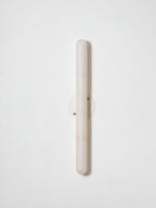 Unlit Clérachic alabaster wall light on a pale wall, showing the pale stone cylinder and its small round metal backplate.