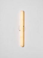 Lit Clérachic alabaster wall light on a pale wall, with the stone cylinder glowing warm in front of its small round backplate.