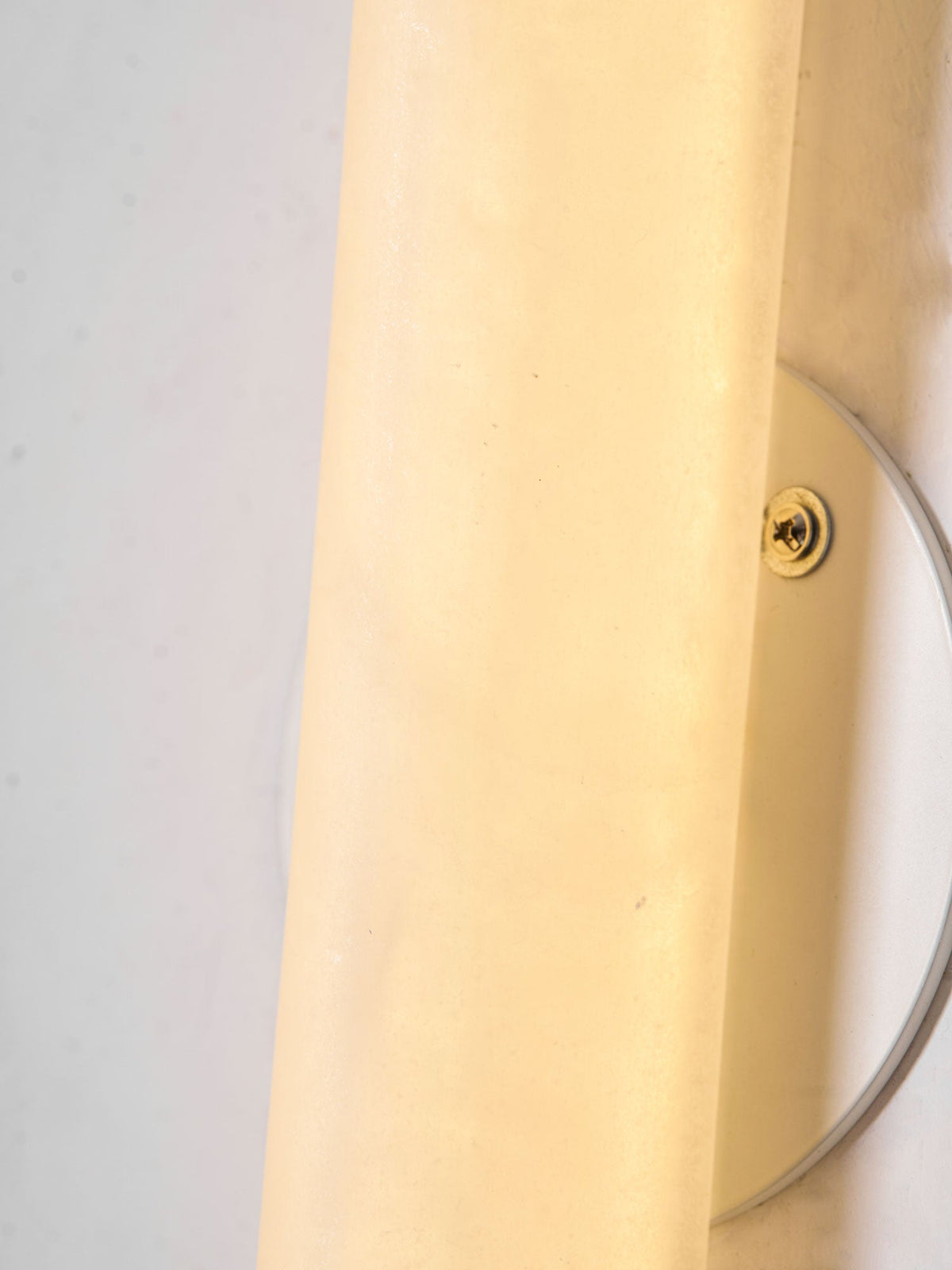 Close view of the glowing alabaster of this Clérachic wall light and the screw fixing its round backplate to the wall.