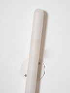 Angled view of the unlit Clérachic alabaster wall light, with its pale veined stone and the round white backplate behind it.
