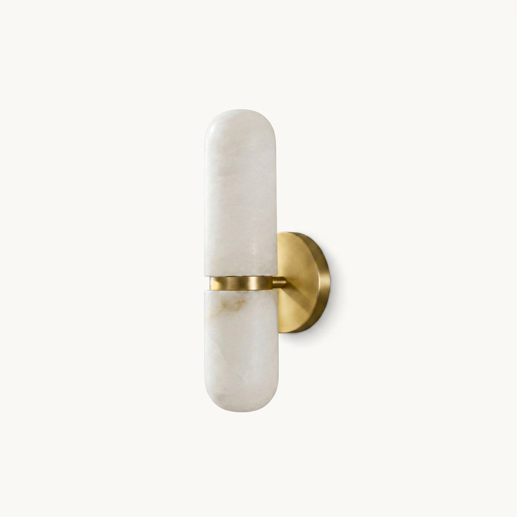 Slim Clérachic alabaster wall light in a brass and white finish, a pill-shaped stone shade on a round brass backplate, on a plain backdrop.