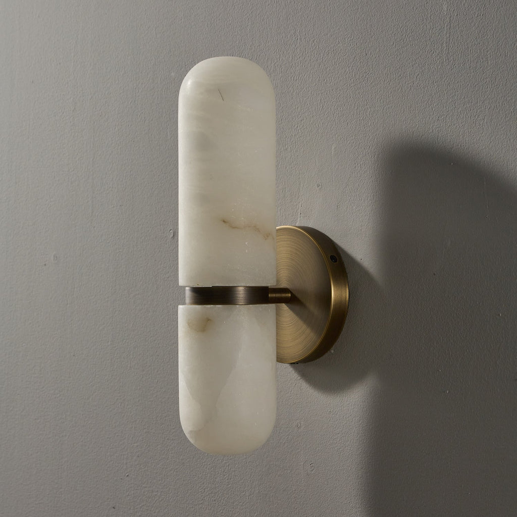 Unlit Clérachic alabaster wall light in a bronze and white finish on a grey wall, with soft veining in the stone.