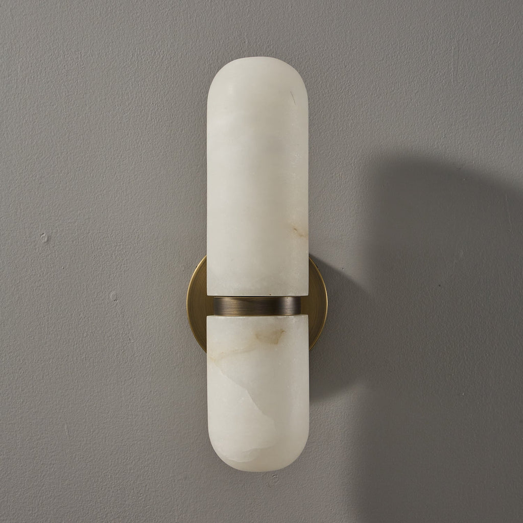 Front view of the bronze and white Clérachic alabaster wall light, unlit, on a grey wall with a soft shadow.