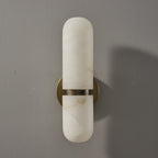 Front view of the bronze and white Clérachic alabaster wall light, unlit, on a grey wall with a soft shadow.