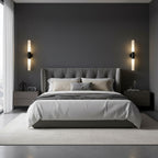 Black-and-white Clérachic wall lights on a dark grey wall either side of a tufted headboard, with matching bedside tables below.
