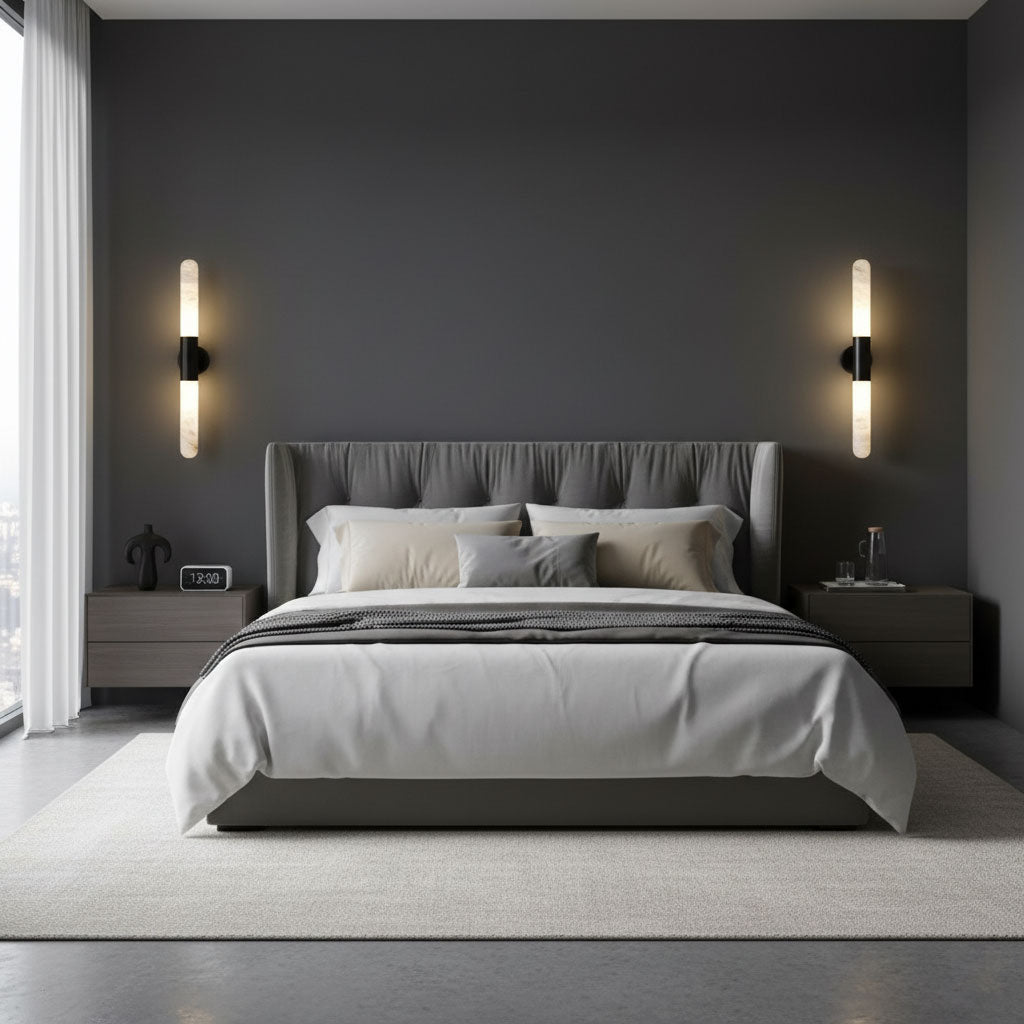 Black-and-white Clérachic wall lights on a dark grey wall either side of a tufted headboard, with matching bedside tables below.
