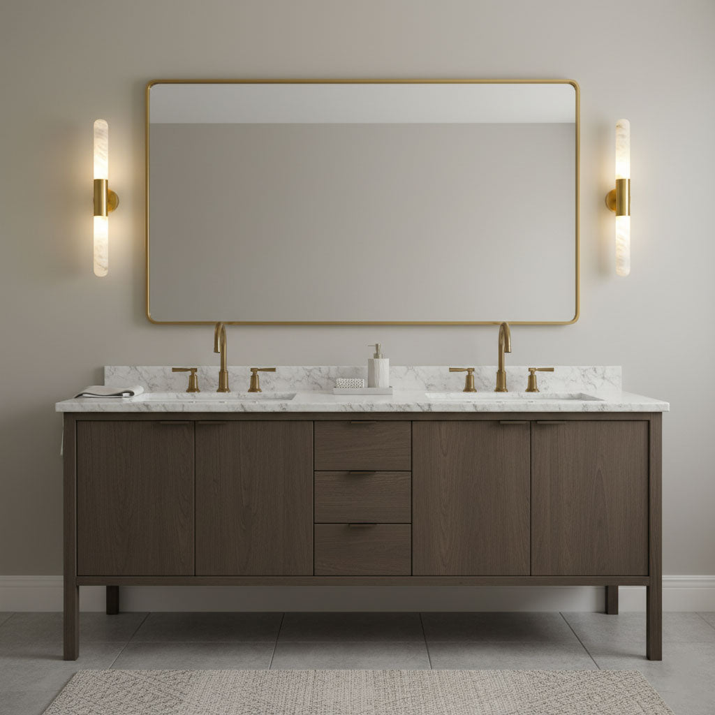 Two Clérachic gold-and-white wall lights flank a wide rectangular mirror with a gold frame, above a double vanity with a marble top.