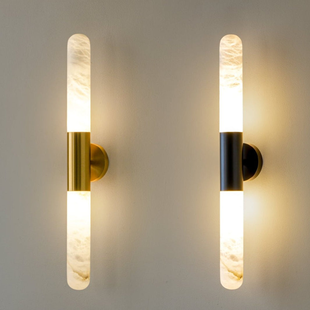 Close view of a pair of Clérachic wall lights, one gold and one black, both lit against a warm grey wall.